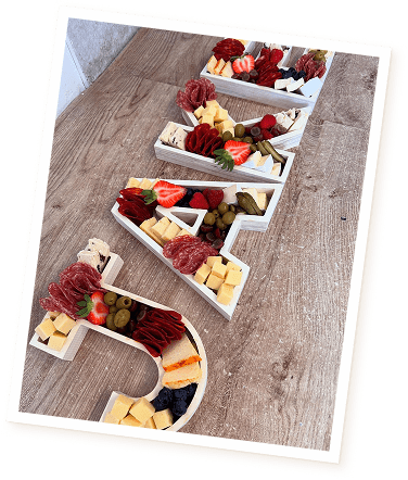 Cheese and meats laid out as a name board by Little Grazey